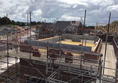 Scaffolding system set up around new residential buildings under construction, ensuring safety and accessibility for builders on a large-scale development site.